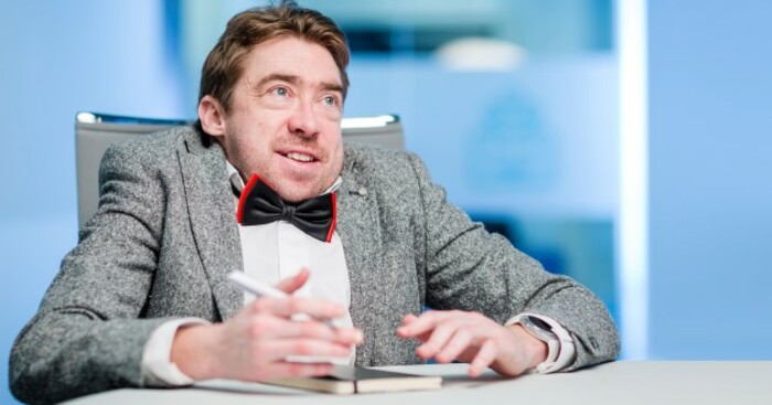 Vivian Rath in a suit sitting at a table 