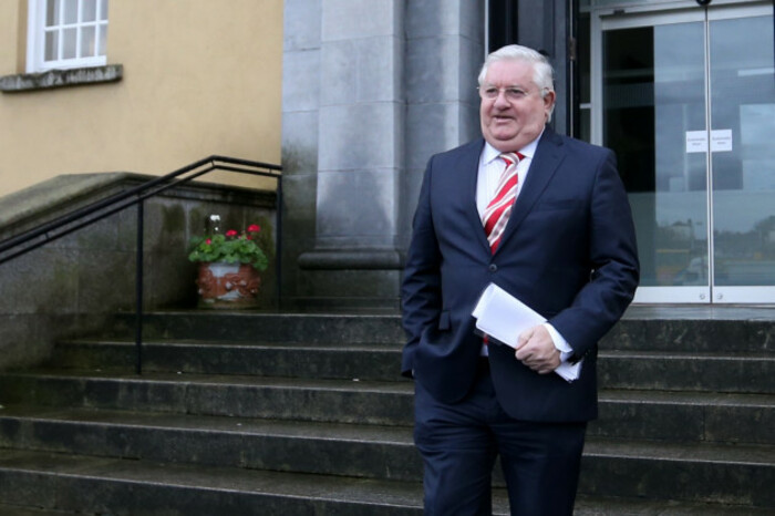 Stephen McMahon wearing a navy suit and pink tie walking down stone steps.