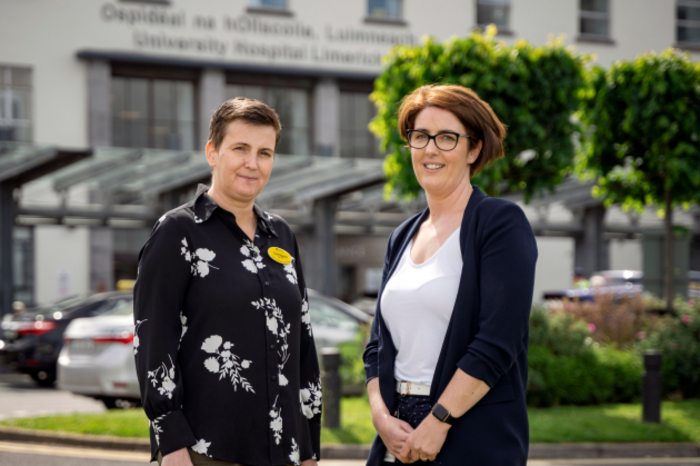 Tina Fitzgerald wearing a black pattern shirt and Linda Mullane wearing a white top and black jacket, standing in front of UHL.