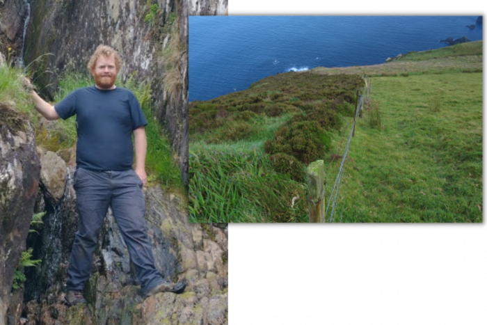 On the left is Dr Rory Hodd wearing a navy top and grey trousers standing on a rock face looking at the camera smiling. On the right is a slope down to the sea with two areas separated by a fence - with heather growing on the left of the fence but short grass on the right. 