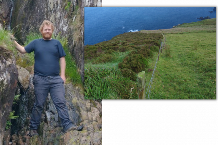 On the left is Dr Rory Hodd wearing a navy top and grey trousers standing on a rock face looking at the camera smiling. On the right is a slope down to the sea with two areas separated by a fence - with heather growing on the left of the fence but short grass on the right. 