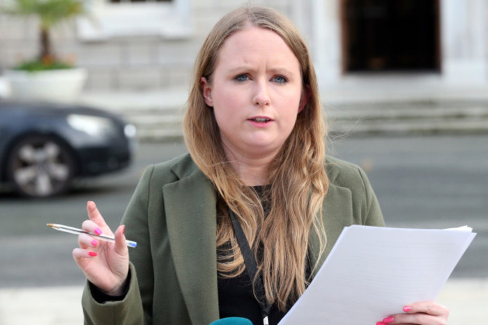 Mair&eacute;ad Farrell - wearing a black top and green jacket - speaking outside Leinster House with paper in one hand and a pen in the other.