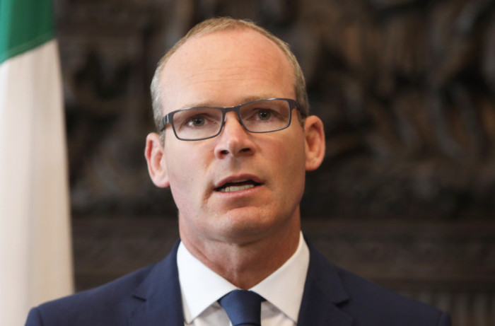 Simon Coveney speaking - while wearing glasses as well as a navy suit and tie.