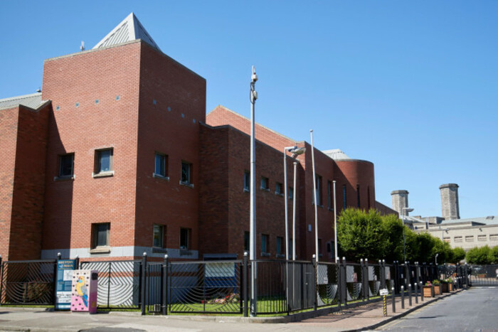 Large brick building with small windows and a number of lights and security cameras beside it. 