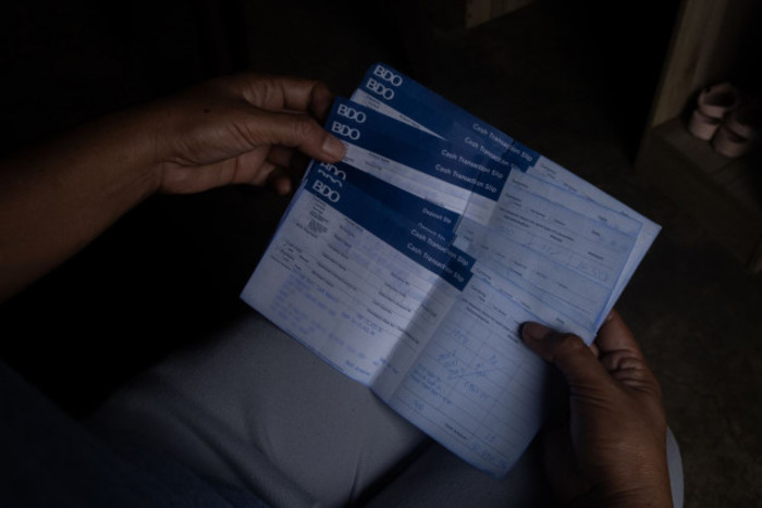 A woman holds banking slips in her hands with details blurred out to protect identity. 