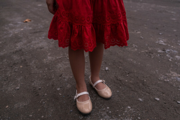 Girl wearing a red skirt and pink ballerina-style sandals - showing only the bottom of skirt and feet to protect identity. 