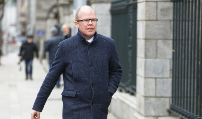 Peadar T&oacute;ib&iacute;n walking down a street in Dublin wearing a dark jacket and glasses.