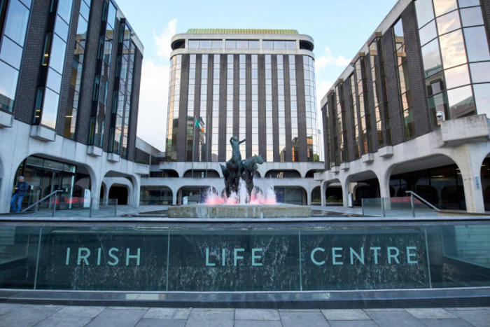 Large building with sculpture in the centre with Irish Life Centre written on a sign in the foreground