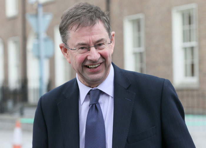 &Eacute;amon &Oacute; Cu&iacute;v smiling in a dark blue suit, light blue tie and glassed