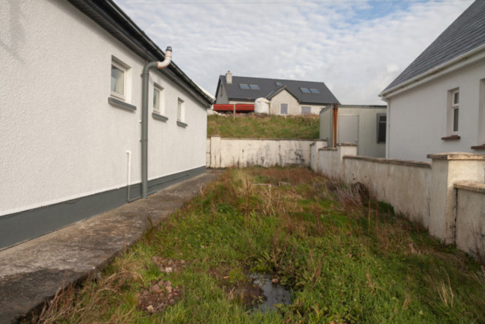 Grass patch at the side of the health centre with a house in the background