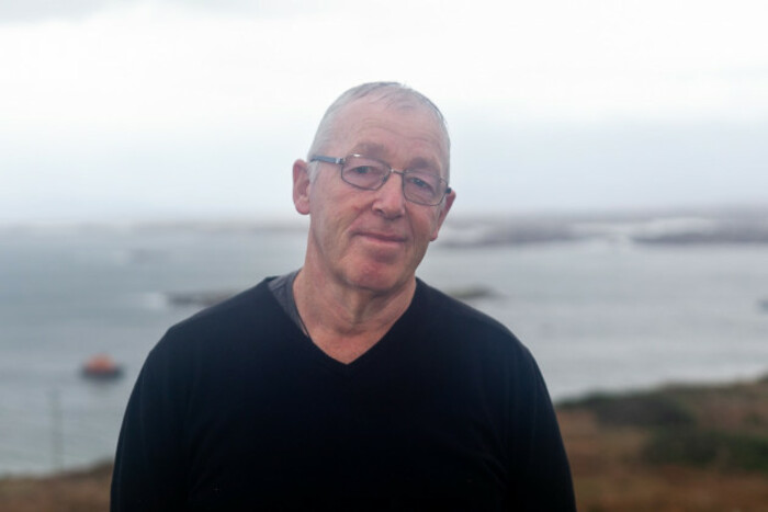 Smiling Jerry Early in a black jumper and a view of the ocean in the background