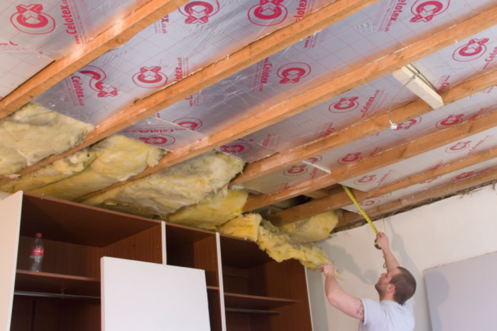 Builder installing insulation between in a ceiling of a building.