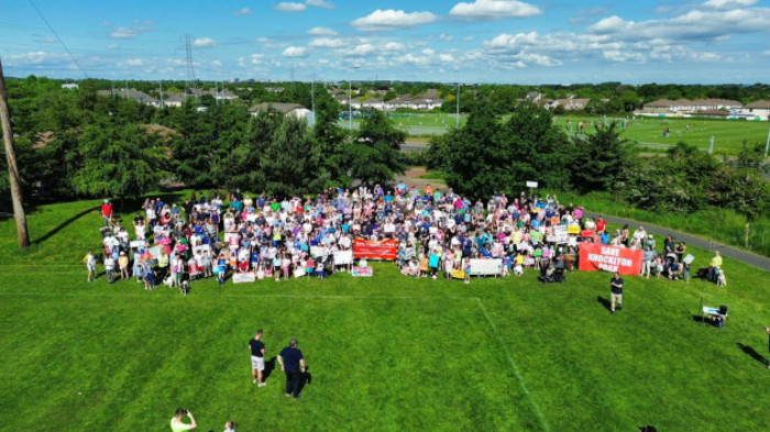 Aerial photo from a drone of a large group of protesters with banners against council plans to install an astroturf pitch